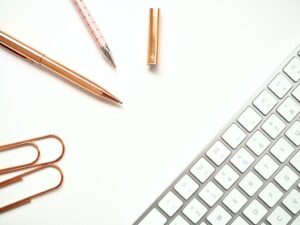 pens near keyboard and paper clips