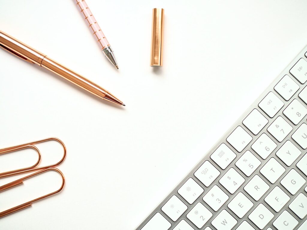 pens near keyboard and paper clips